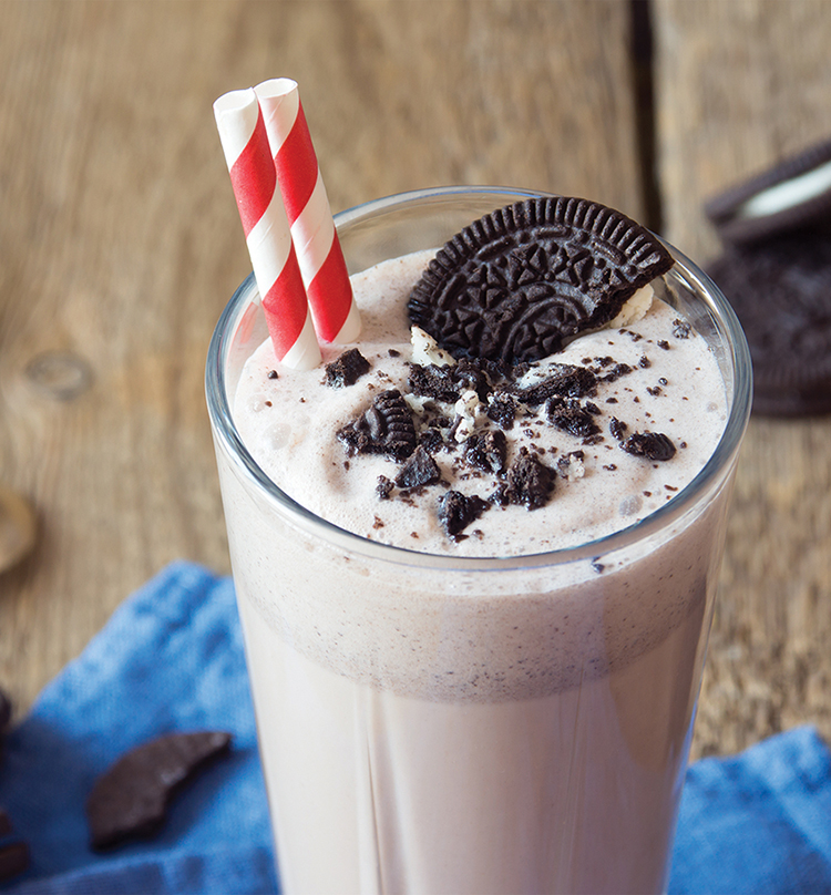 Chocolate milkshake with whipped cream and chocolate candies on top.