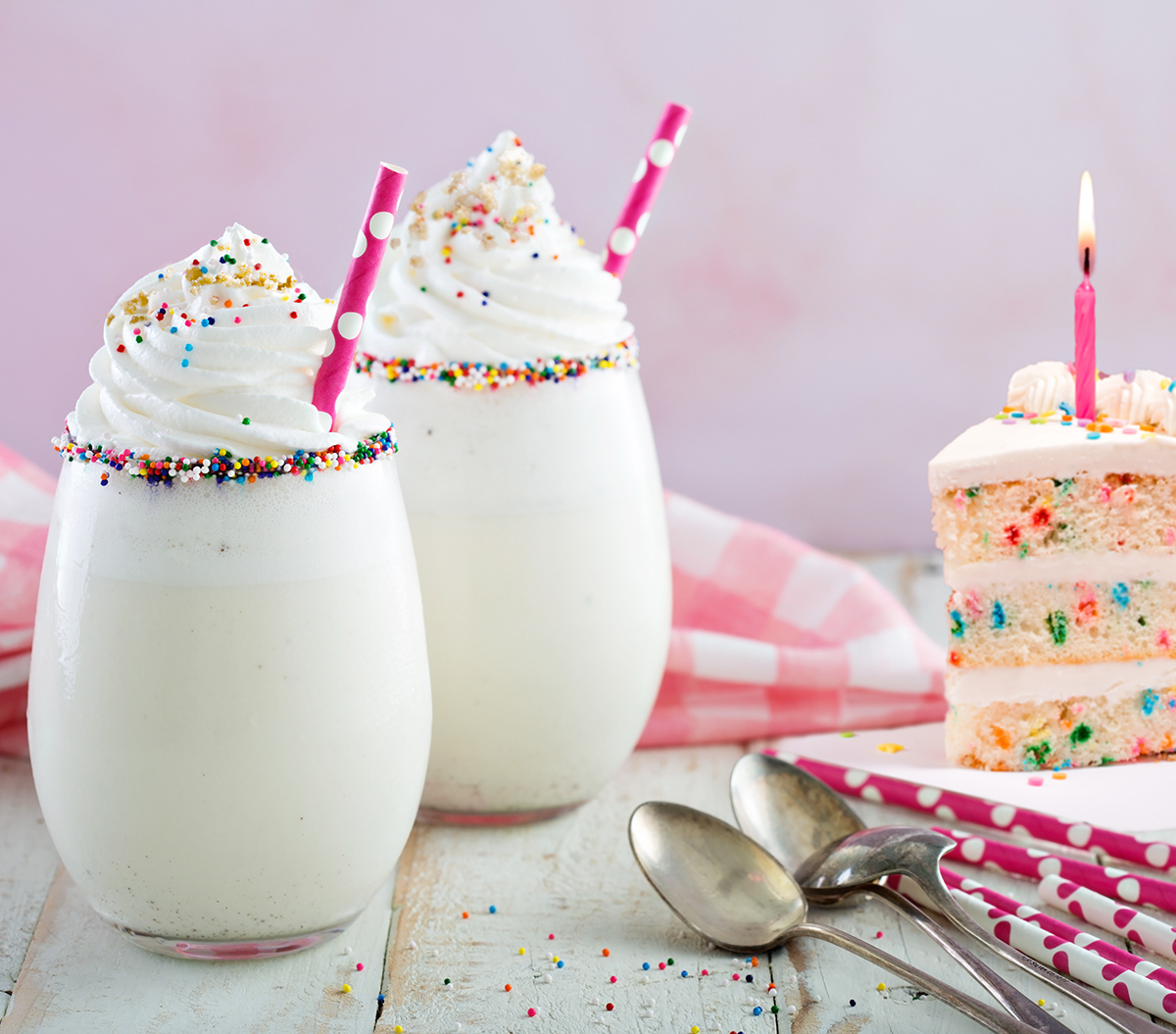 Birthday cake milkshakes with a slice of birthday cake.